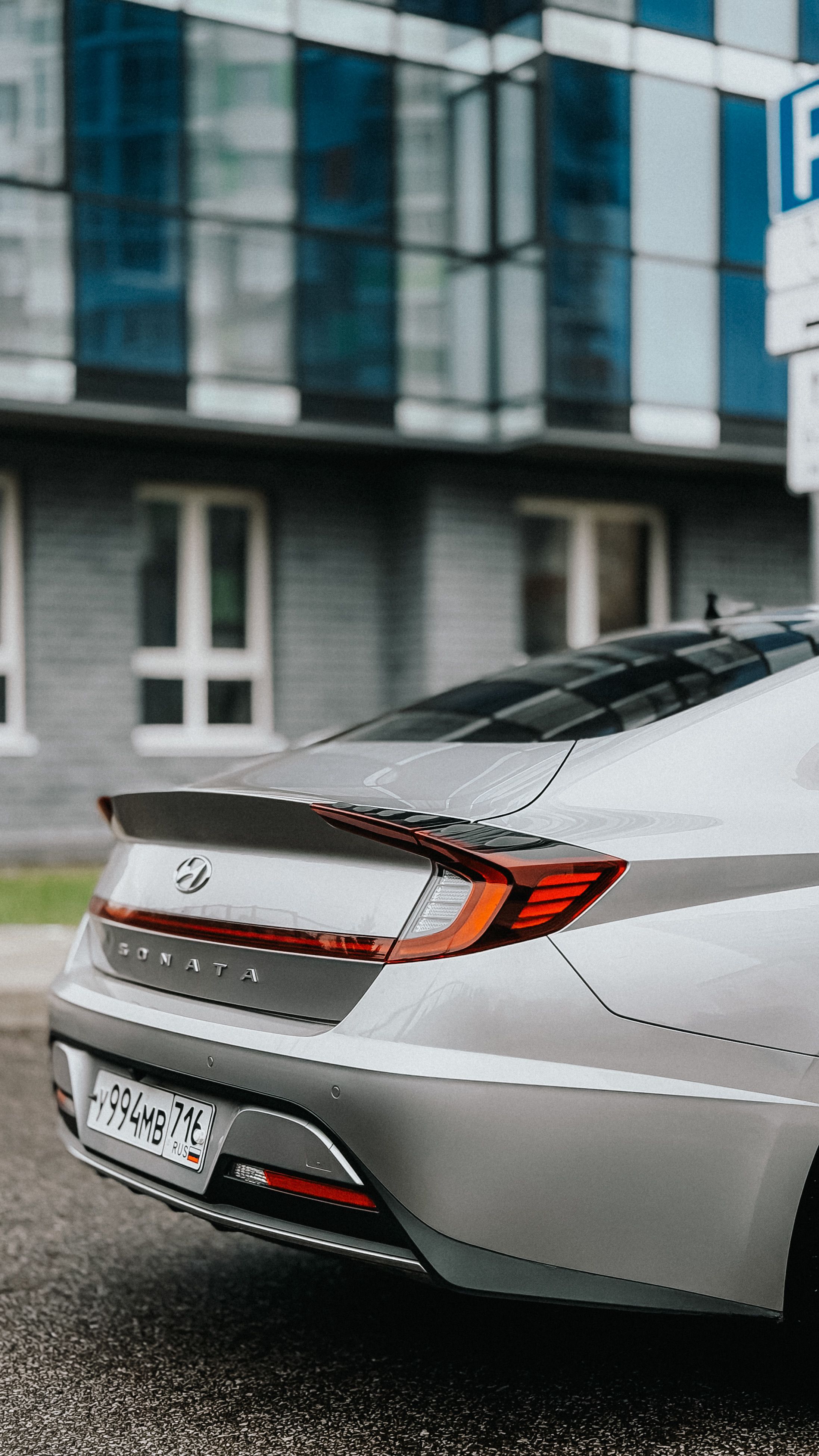 Rear view of a sleek silver sedan parked in front of a modern building.
