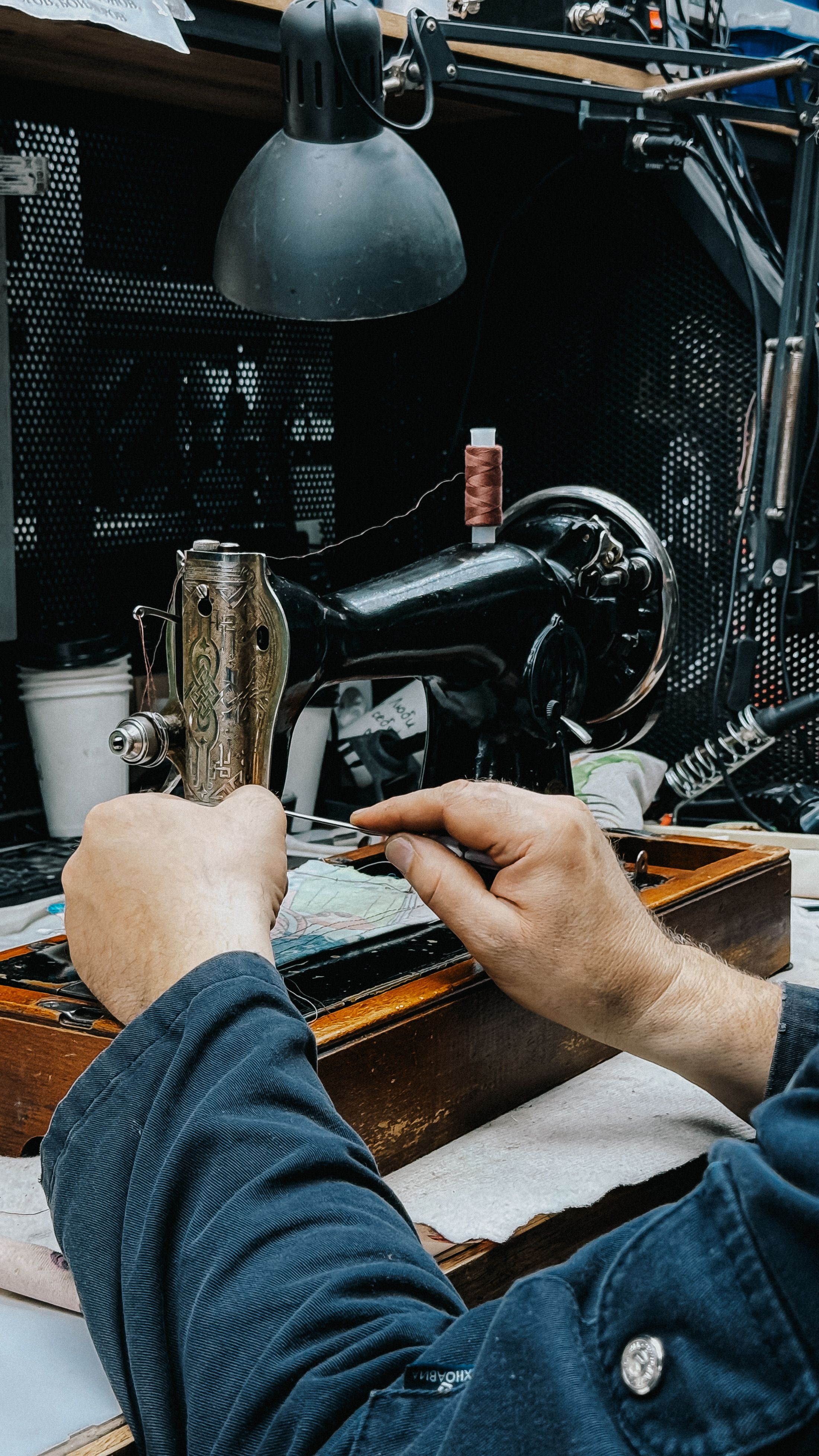 Close-up of hands operating a vintage sewing machine in a classic workshop setting.