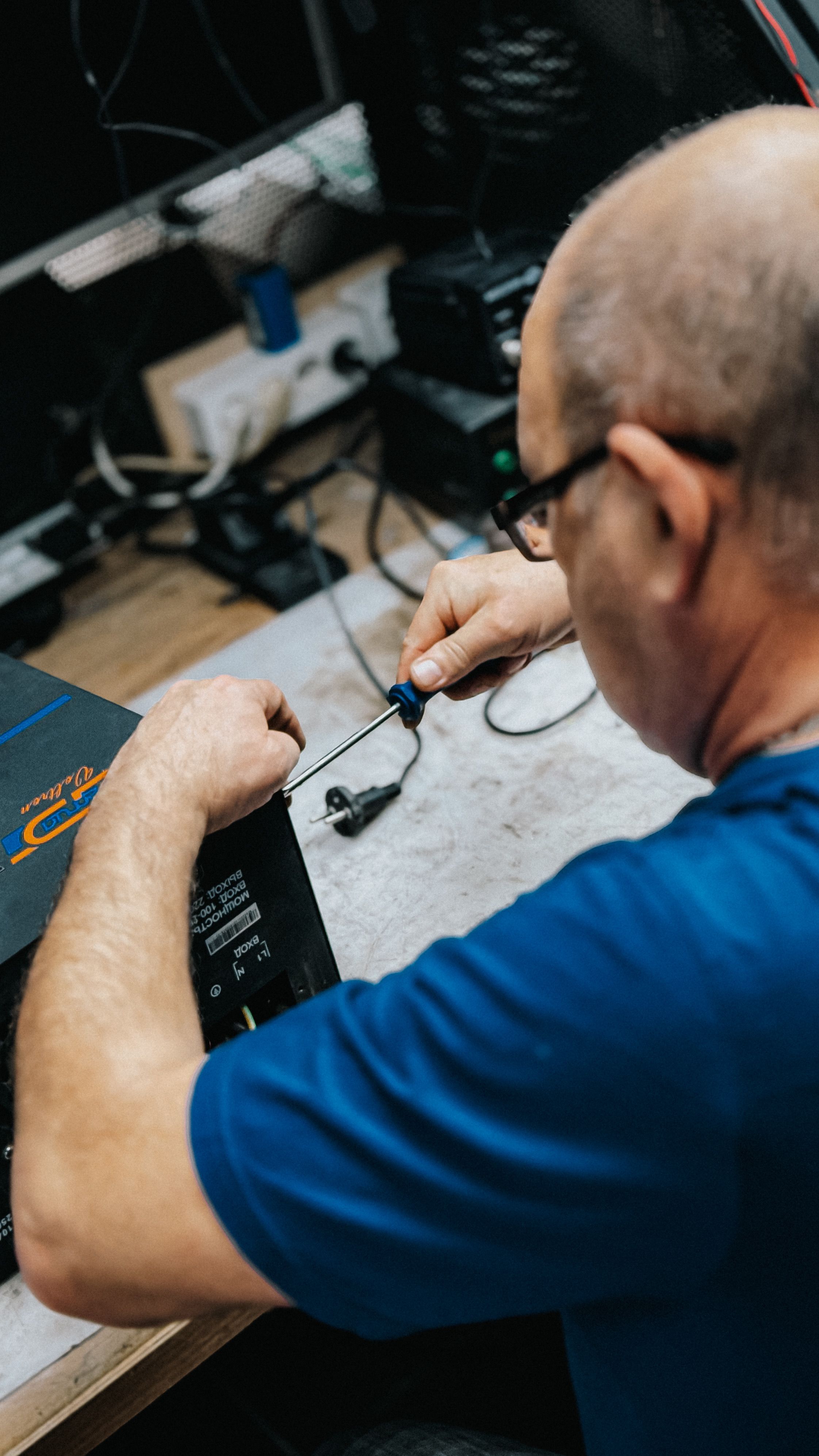 A skilled technician working on electronic repair tasks in a workshop environment.