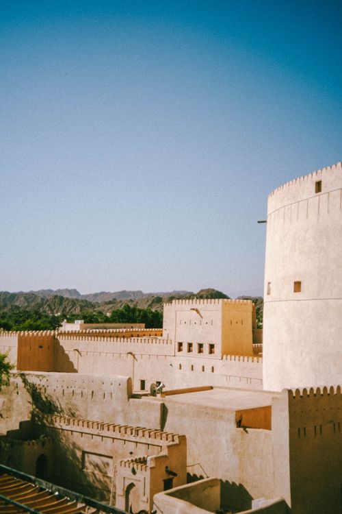 Free Historic Nizwa Fort in Oman bathed in sunlight, showcasing its architectural beauty under a clear blue sky. Stock Photo