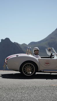 A vintage sports car driven by a mysterious person on a scenic mountain road in South Africa.