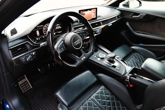 Sleek interior view of a luxury car featuring black leather seats, steering wheel, and advanced dashboard.