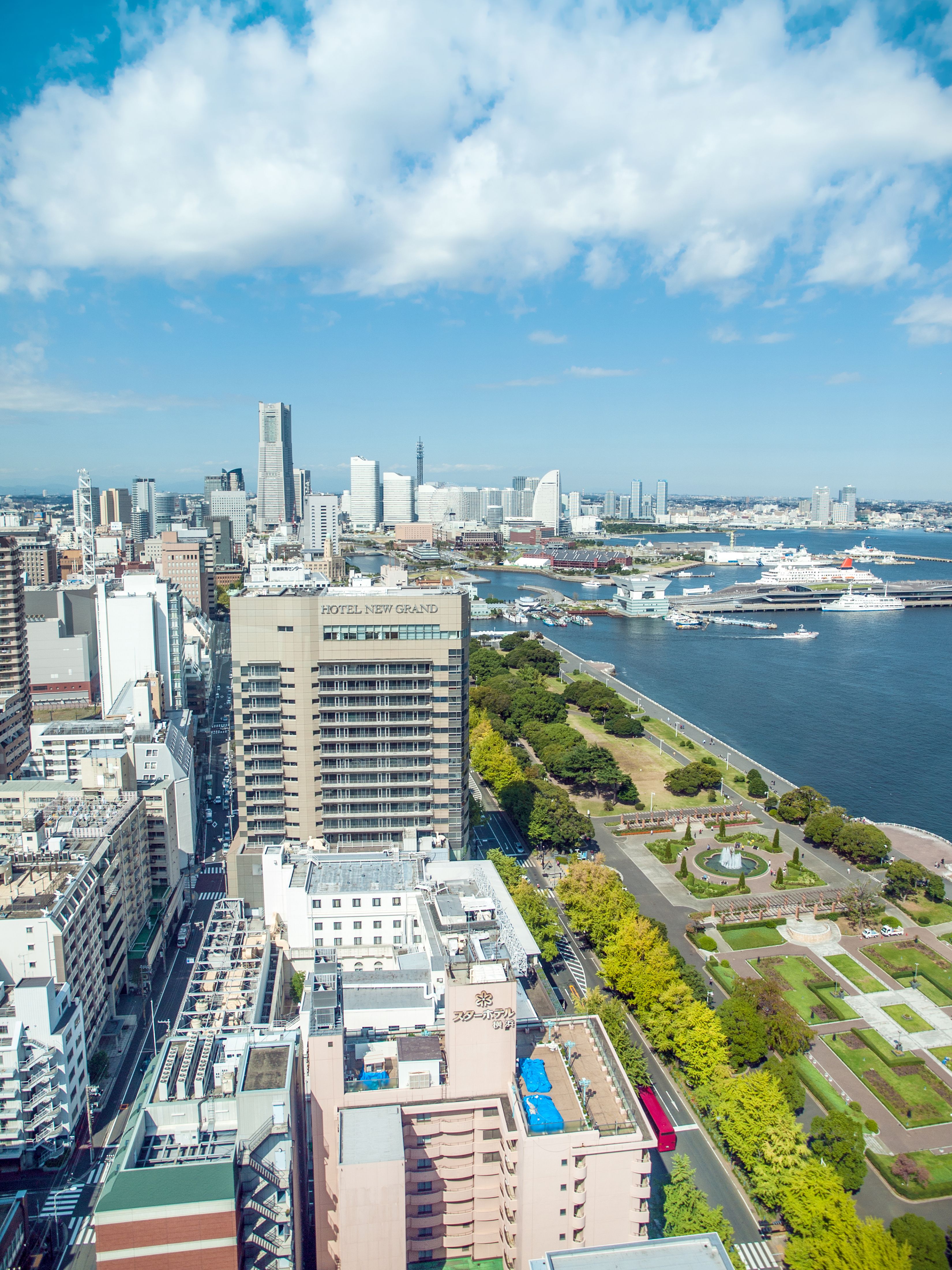Scenic aerial view of Yokohama city skyline with harbor, skyscrapers, and green park in Japan.