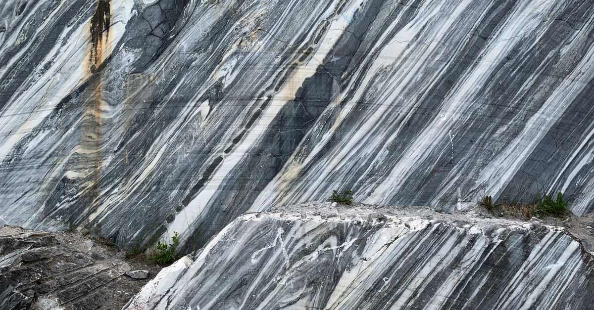 Close-up of a textured marble rock surface with natural gray patterns and weathered textures.