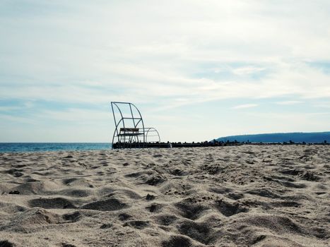 A tranquil beach scene showcasing a calm ocean and sandy shore under a bright sky.