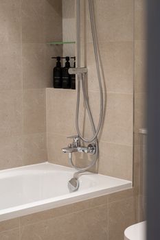 Elegant minimalist bathroom with beige tiles and modern shower fittings.