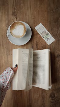 A serene top-down view of a coffee and open book on a wooden table, perfect for a relaxing read.