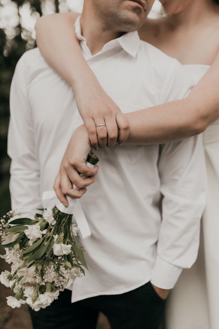 A close-up of a couple embracing on their wedding day, holding a bouquet.