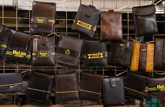 Collection of leather wallets on a market rack, showcasing diverse designs and finishes.