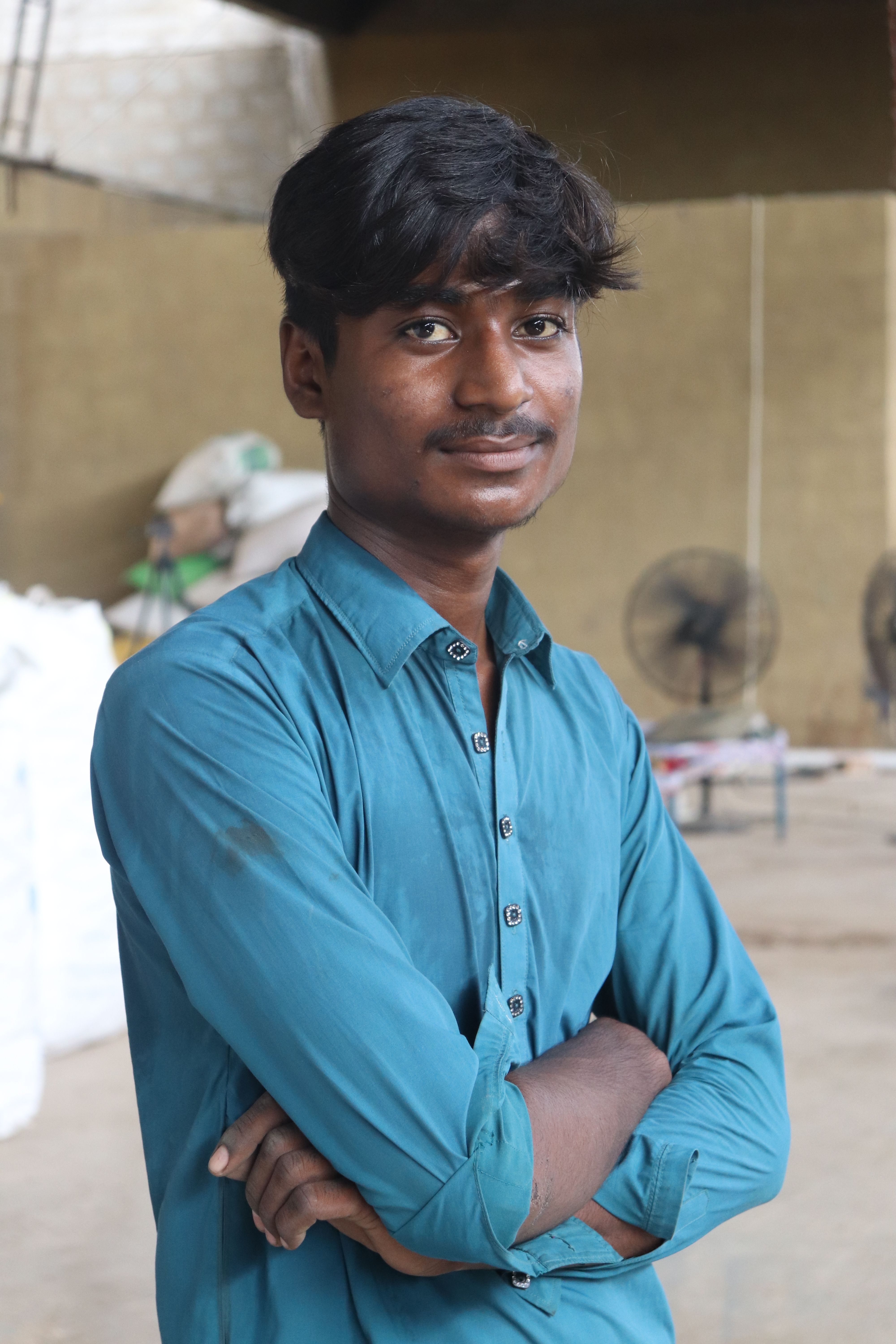 Portrait of a young male worker standing confidently in a Karachi warehouse.