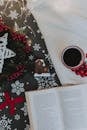 Homey composition of Christmas attributes with open book and coffee