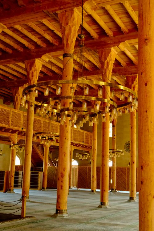 Free Warm-toned wooden pillars and chandelier inside historical mosque. Stock Photo