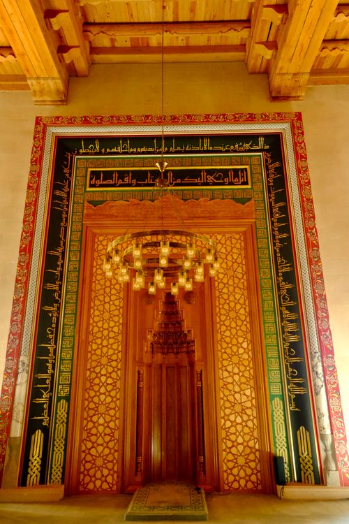 Free Majestic wooden mosque entrance adorned with intricate Arabic calligraphy and chandelier. Stock Photo
