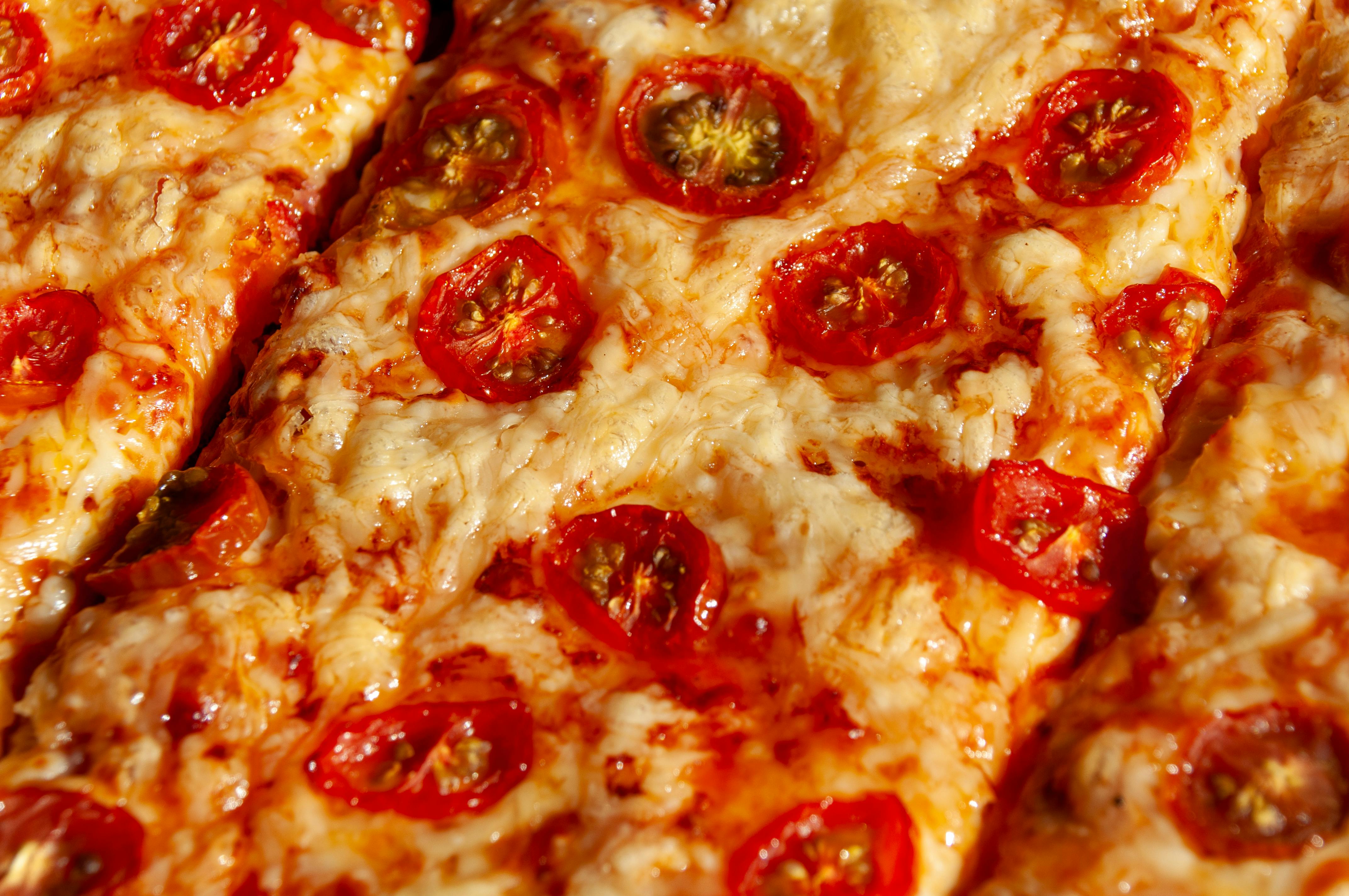 Close-up of a cheesy Italian pizza topped with fresh cherry tomatoes, perfect for food lovers.