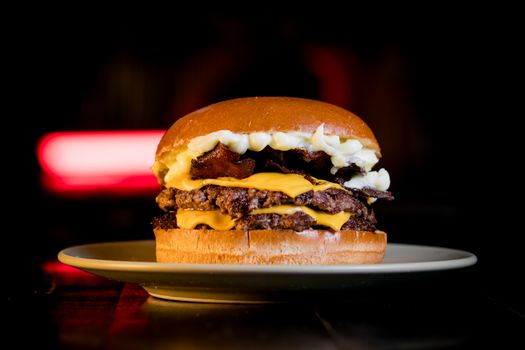 Close-up of a gourmet cheeseburger layered with bacon and cheese on a plate.