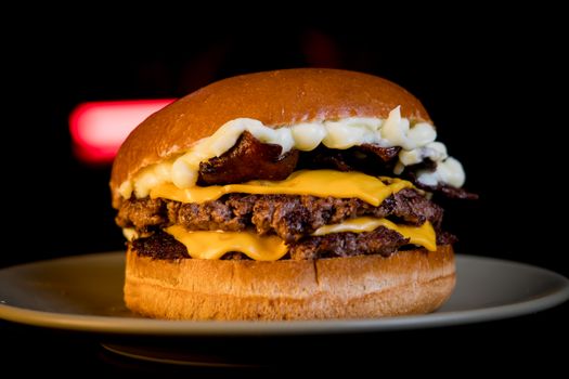 Tasty cheeseburger with layered beef patties, cheese, and bacon on a plate.