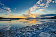 魁北克市一个冰冻的湖泊映照着明亮的日落，捕捉到宁静的冬季景观