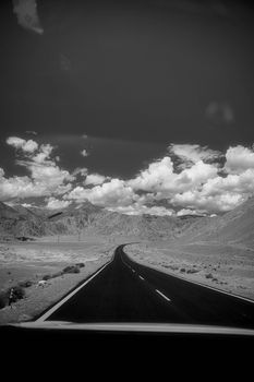 Endless road cutting through a barren desert under a dramatic sky.