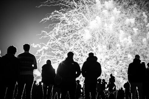 Free Black and white photo capturing silhouettes of people watching a vibrant fireworks display at night. Stock Photo