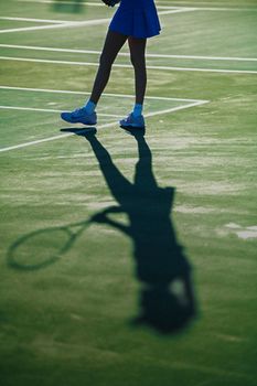 Artistic shadow of a tennis player captured on a sunlit court.
