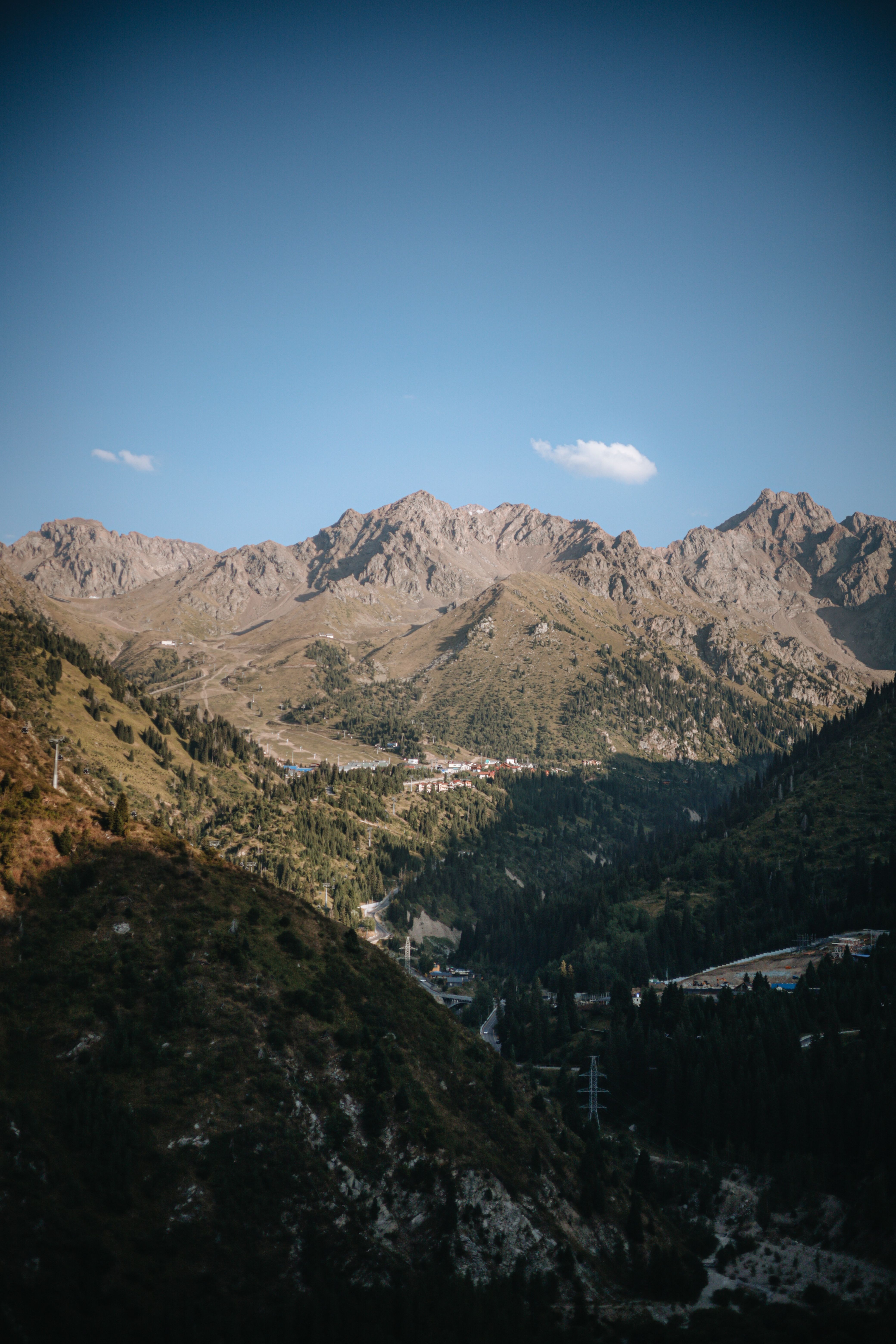 Beautiful mountain landscape under clear blue sky with soft sunlight casting shadows.