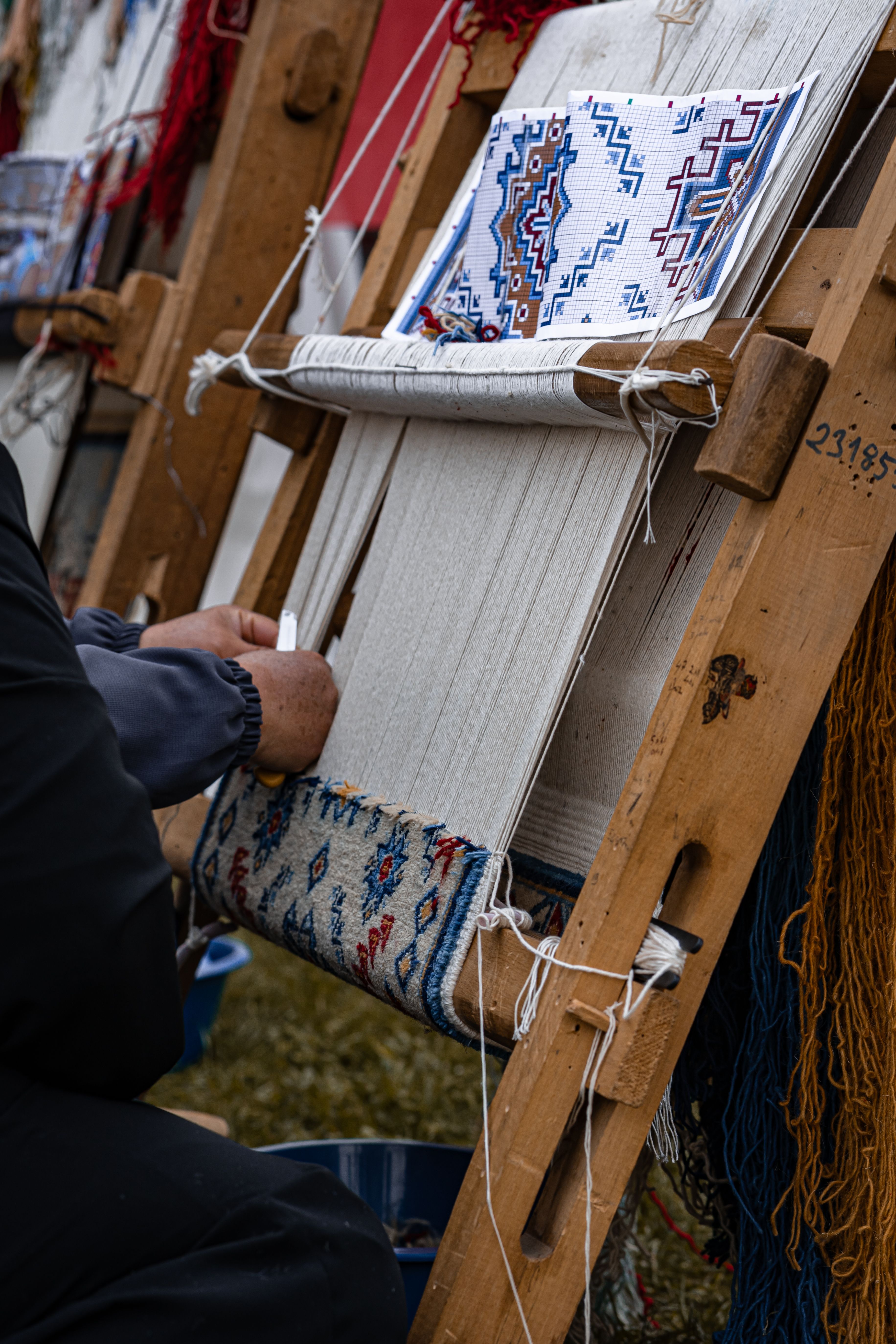 Hands creating a detailed carpet pattern by hand