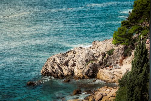 Free Breathtaking view of rocky coastline with turquoise sea and lush greenery. Stock Photo