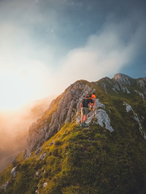 Free Two hikers climb a rugged mountain ridge in Valtellina, Italy, at sunrise. Stock Photo