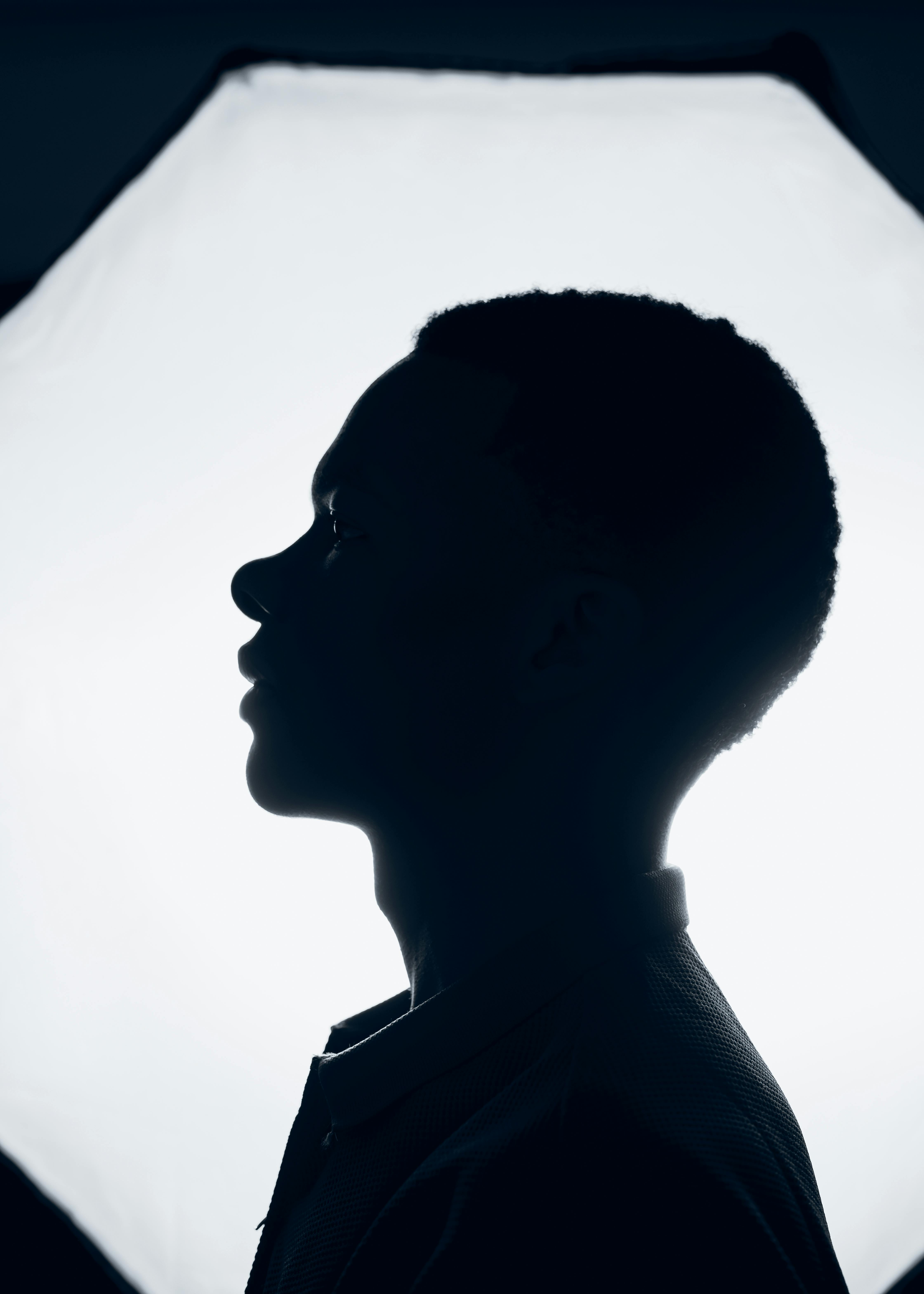 Side profile silhouette of a man in front of a bright studio light, artistic and dramatic.