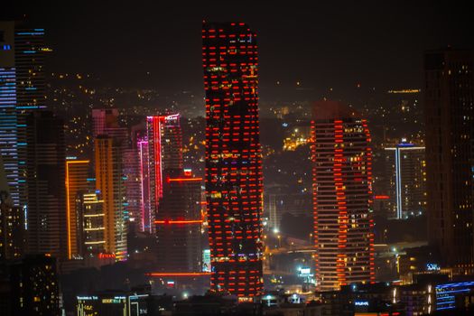 Explore the dazzling night skyline of İzmir, Türkiye, illuminated by vibrant neon lights and modern architecture.
