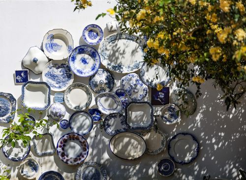 Free A collection of vintage plates on a white outdoor wall with floral accents. Stock Photo