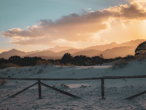 Captivating sunset at a serene beach in Sardinia, Italy, with soft sand and distant mountains.