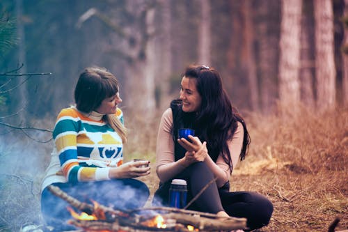 Zwei Frauen Sitzen Am Boden In Der Nähe Von Lagerfeuer