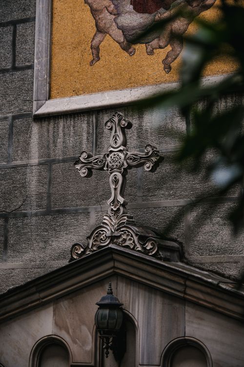 Free Elegant stone cross detail on historic church facade with mural above. Stock Photo