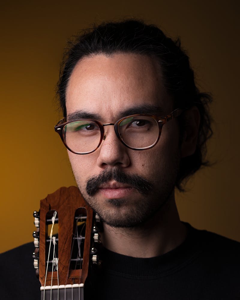 Musician portrait with guitar against dark background