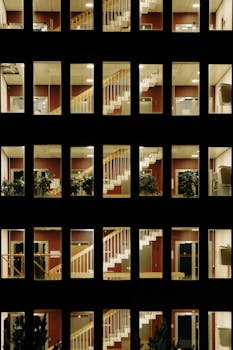 A grid of illuminated windows showcasing an interior view at night, highlighting architectural geometry.