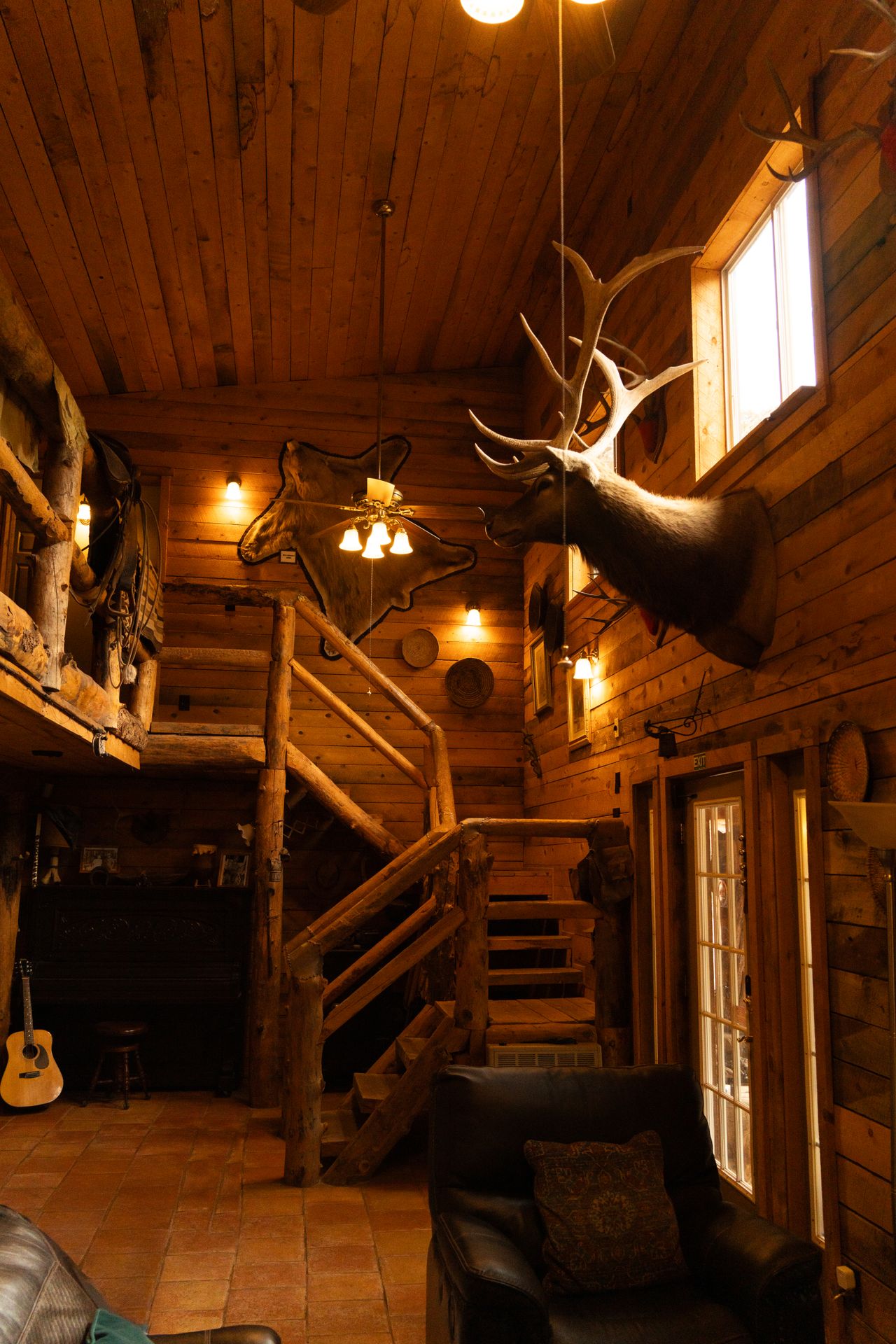 Rustic western cabin interior with log staircase, wood plank walls, and mounted antlers