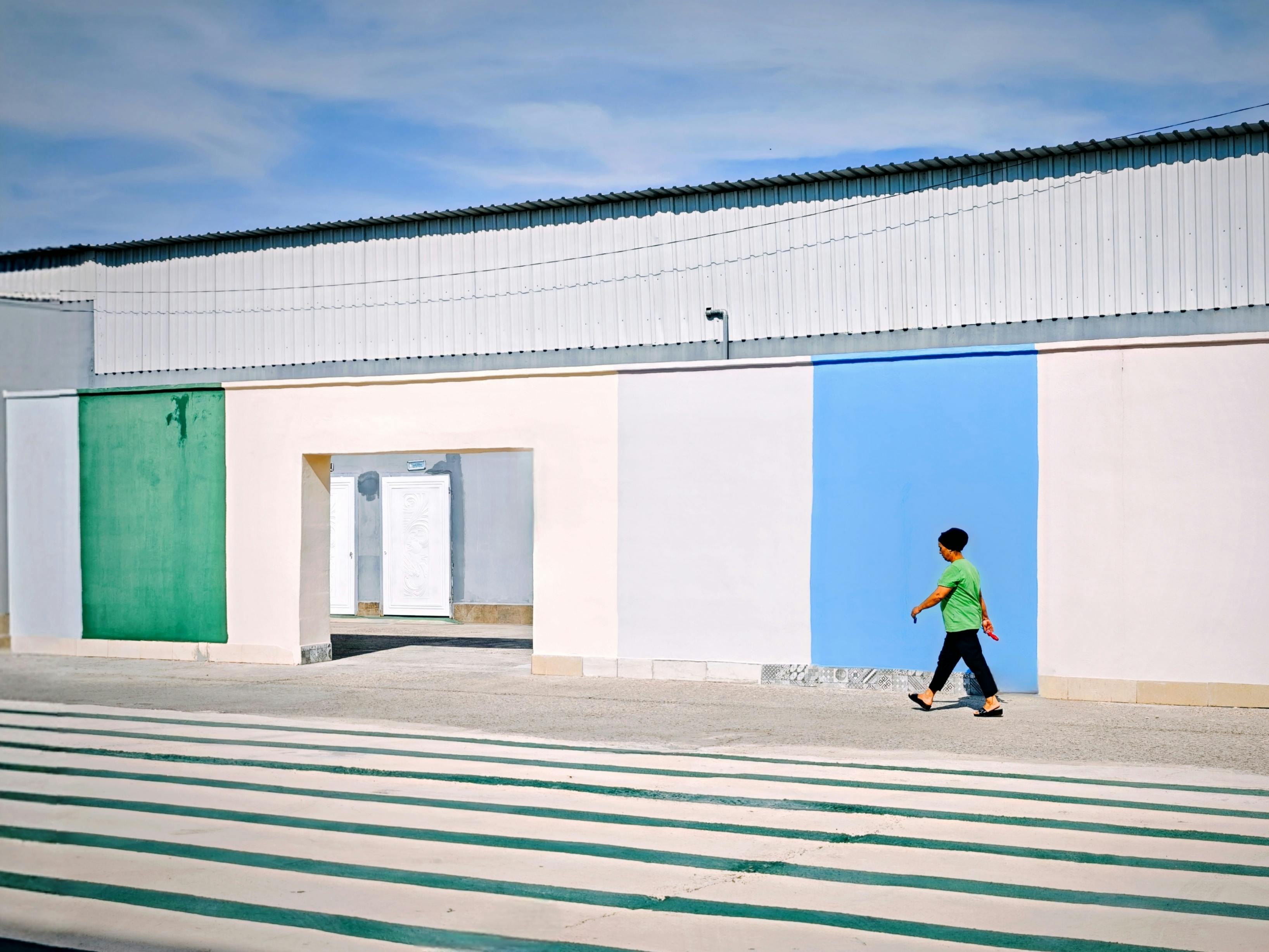 A young boy walks by a vibrant building facade in Adana, Türkiye.