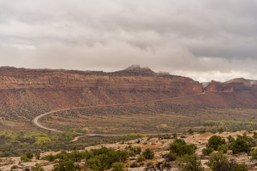 Majestic Utah canyon with winding road under a dramatic cloudy sky, perfect for adventure travel.
