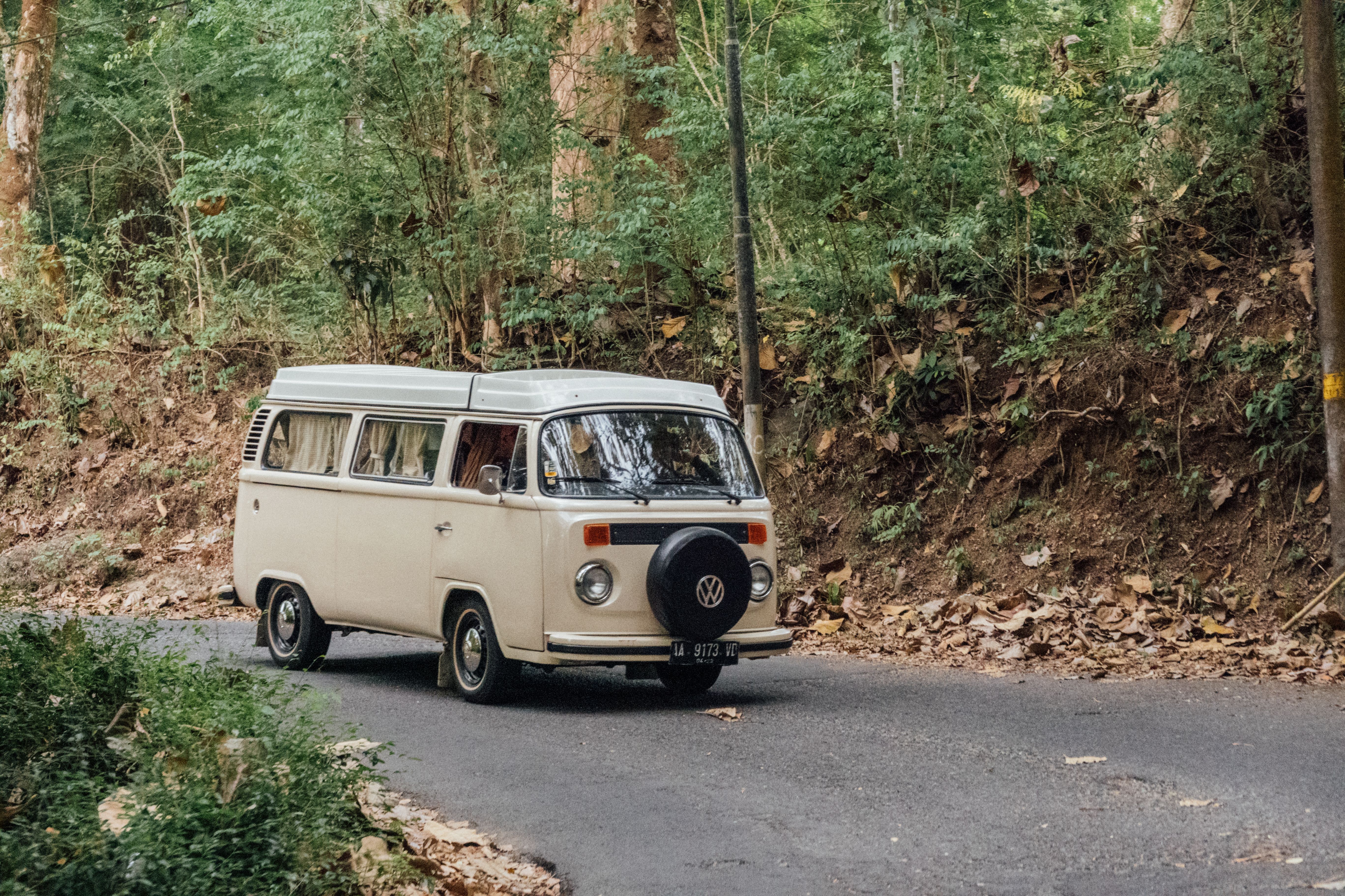 A classic camper van drives through the lush greenery of Yogyakarta, Indonesia, showcasing van life.