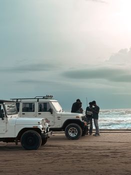 Two jeeps parked by the beach with friends enjoying the view.
