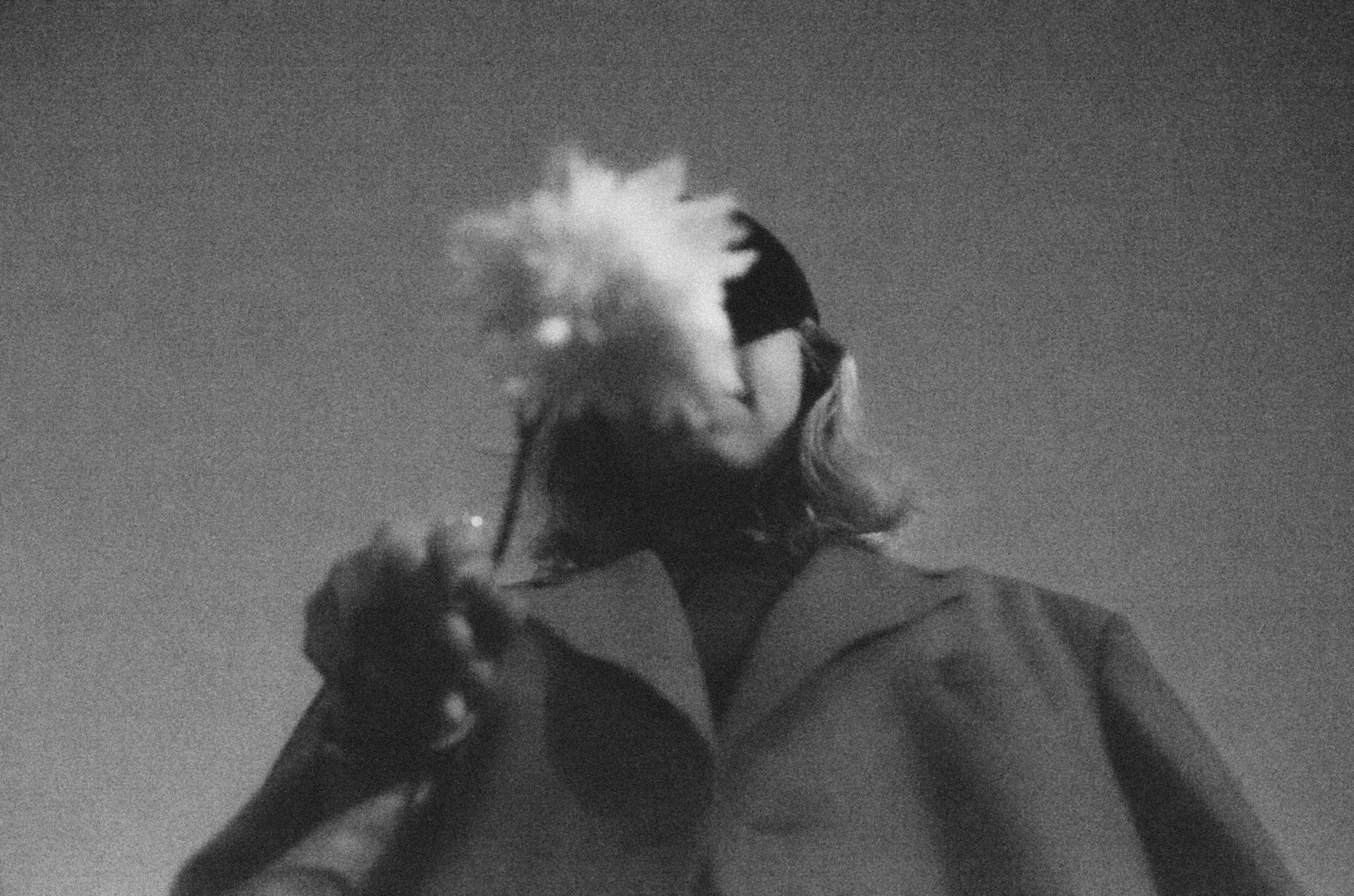 A creative black and white portrait of a person holding a flower with a dramatic upward angle.