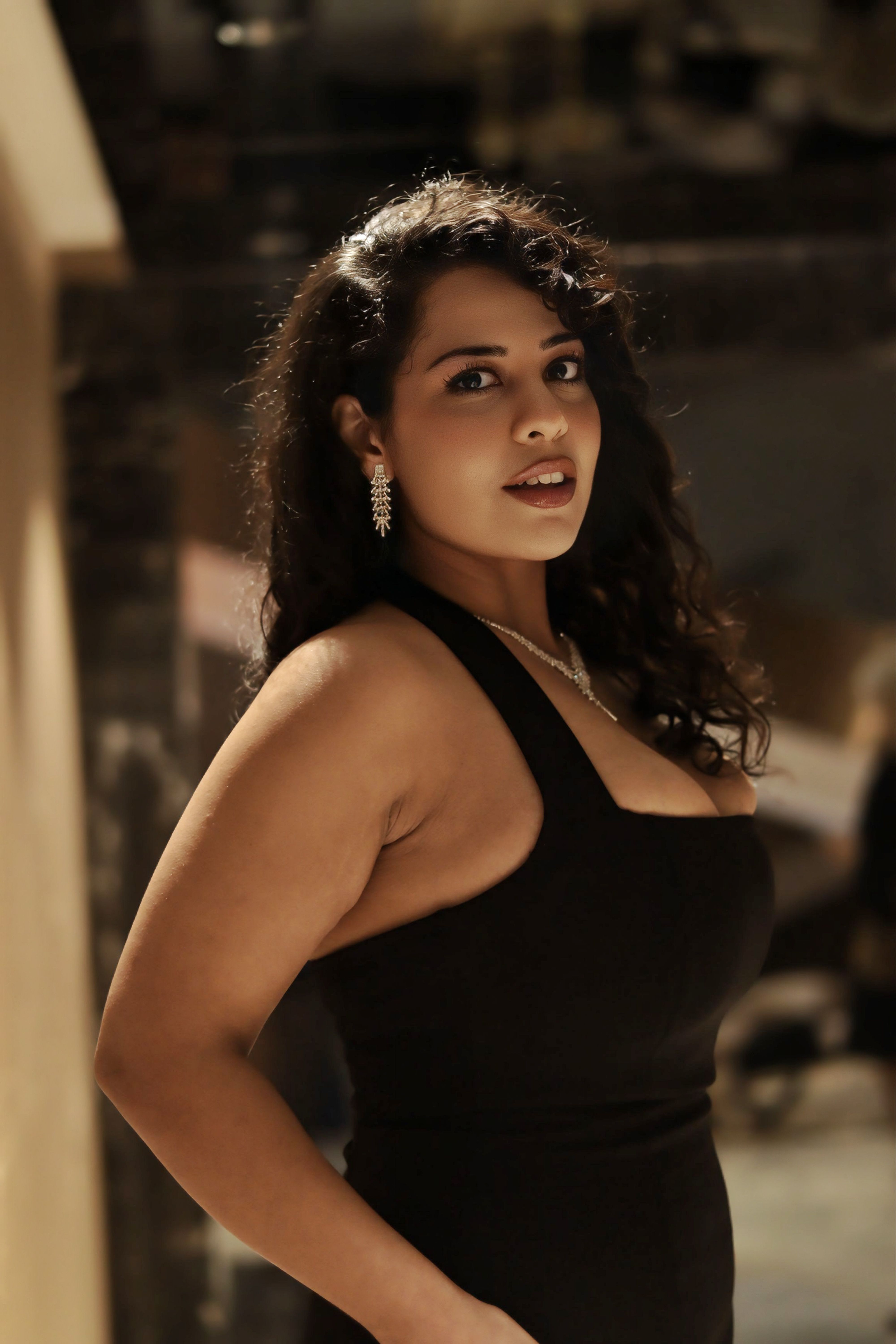 Sophisticated woman in a black evening dress with earrings, indoors.