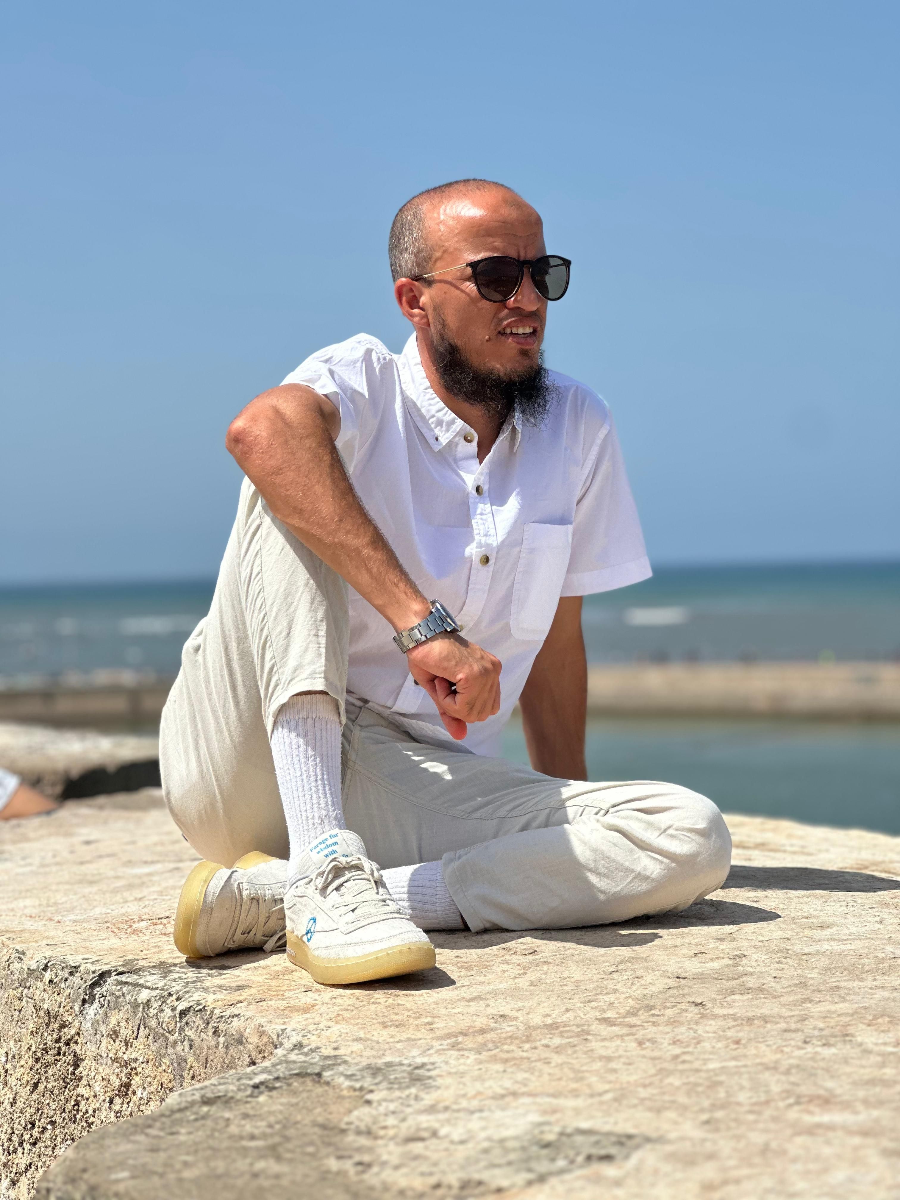 Man in casual white clothes enjoying a sunny day by the sea in El Jadida, Morocco.