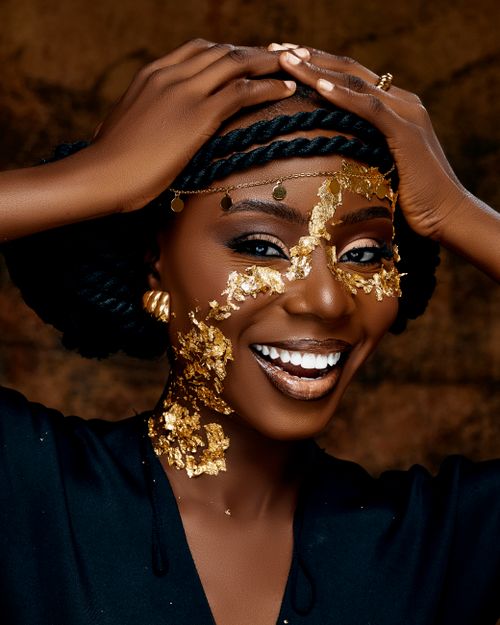Free Stunning portrait of a smiling woman adorned with gold leaf design on face and braided hair. Stock Photo