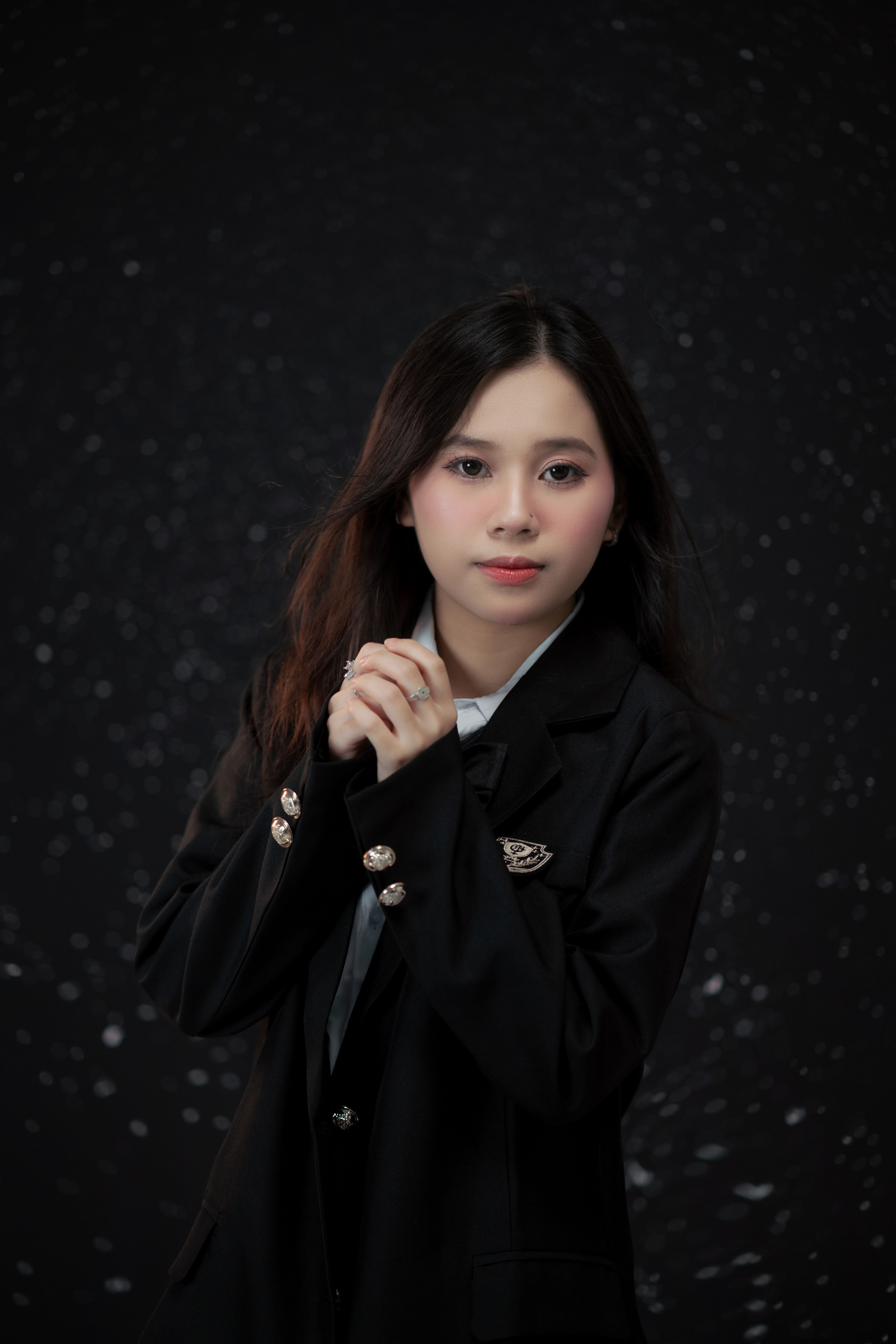 A captivating portrait of a young woman in a stylish black blazer against a dark, speckled backgroun