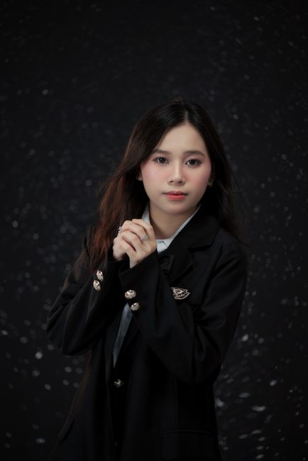 A captivating portrait of a young woman in a stylish black blazer against a dark, speckled backgroun