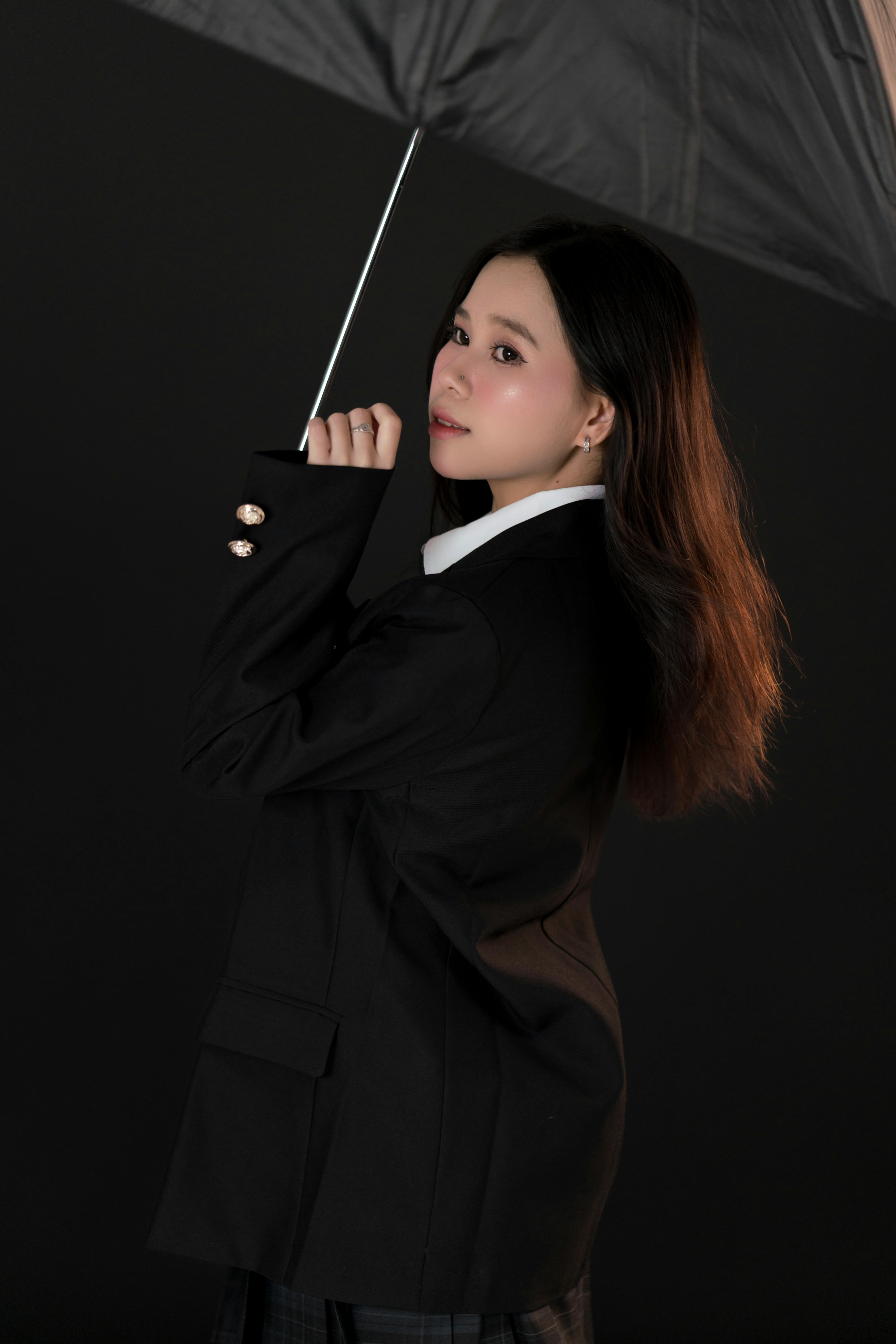Stylish woman holds an umbrella in a studio setting, showcasing elegance and poise.