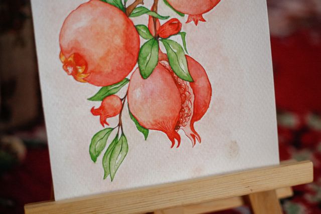 Watercolour still life of pomegranates drying on a wooden easel — photo by betül nur akyürek on Pexels