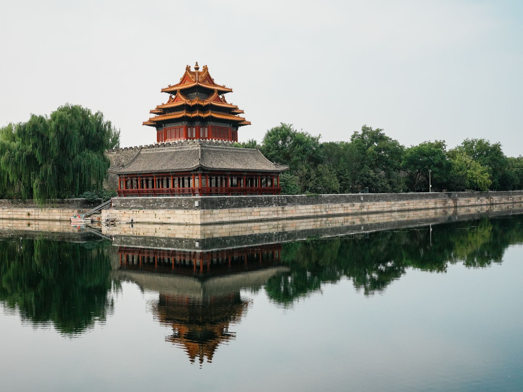 A scenic view of the iconic corner tower of the Forbidden City with its reflection in the moat.